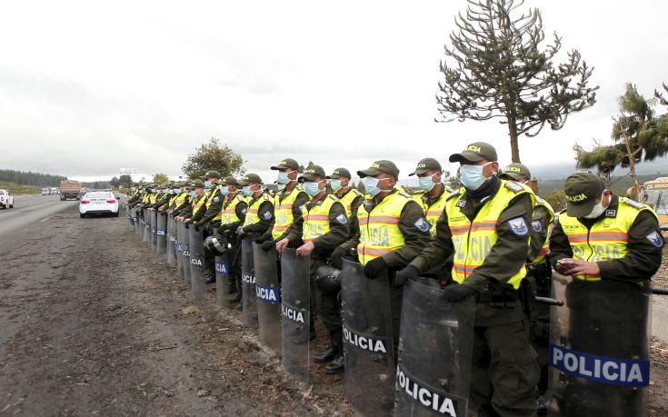 Police wearing surgical masks to protect themselves from volcanic ash spewed by the Cotopaxi volcano stand along a highway in Chasqui
