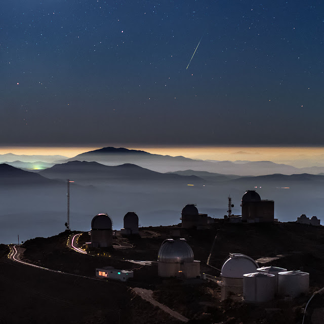 A colourful meteor photographed above La Silla telescope domes and inversion layer in the southern outskirts of the Atacama desert, Chile. The close-up view of the meteor shows a stumbling path which is the actual aerodynamic flight path of the meteoroid, due to the shape of the object as it spins and spirals through the atmosphere. This European Southern Observatory's (ESO) site has telescopes which observe at optical and infrared. The largest optical telescope has a mirror with a diameter of 3.6 metres. The high altitude of La Silla (2400 metres), the dark sky, and the clear air above it (reducing atmospheric distortions of incoming light), make the site an ideal location for astronomical observations.