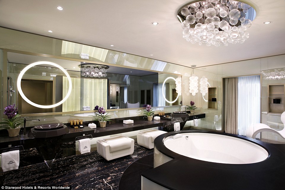 This spacious bathroom features his-and-hers sinks, gigantic mirrors, a chandelier, luxurious toiletries and a whirlpool bath