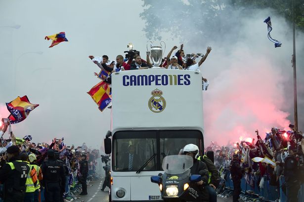 Fans surround the bus as Real Madrid players hold up the trophy celebrating the team's win on Plaza Cibeles in Madrid on May 29, 2016
