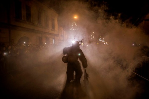   A participant dressed as the Krampus creature walks the streets during Krampus gathering on December 12, 2015 in Kaplice, Czech Republic. Krampus, also called Tuifl or Perchten, is a demon-like creature represented by a fearsome, hand-carved wooden mask with animal horns, a suit made from sheep or goat skin and large cow bells attached to the waist that the wearer rings by running or shaking his hips up and down. Krampus has been a part of Central European, alpine folklore going back at least a millennium, and since the 17th-century Krampus traditionally accompanies St. Nicholas and angels on the evening of December 5 to visit households to reward children that have been good while reprimanding those who have not. However, in the last few decades the western Austrian region of Tyrol in particular has seen the founding of numerous village Krampus associations with up to 100 members each and who parade without St. Nicholas at Krampus events throughout November and early December. In the last few years, Czech towns, placed on the border with Austria, invite Austrian Krampus groups into towns for parades as a new tradition during Advent.?  (Photo by Matej Divizna/Getty Images)