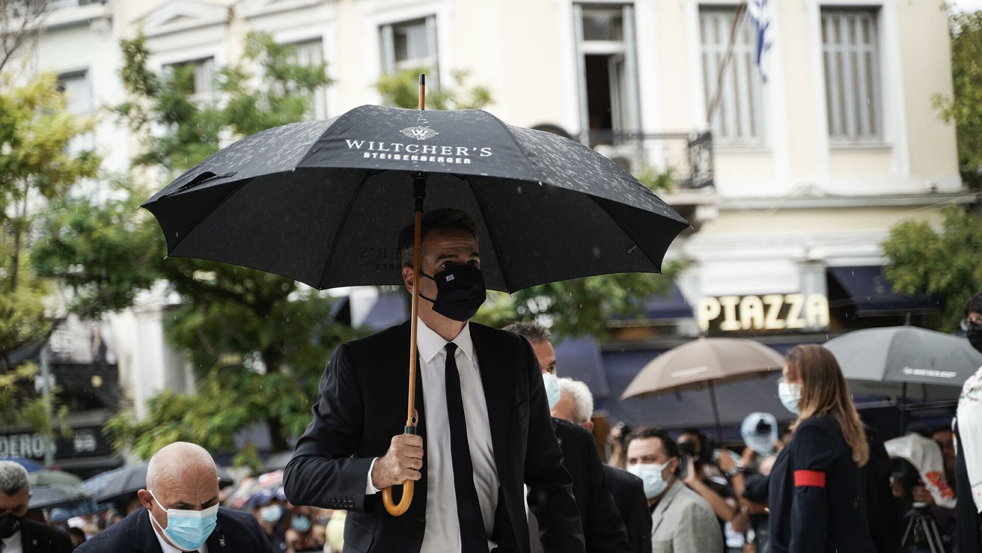Κ.Μητσοτάκης: Πήγε στην κηδεία του Μ.Θεοδωράκη με ομπρέλα-διαφήμιση πεντάστερου ξενοδοχείου!