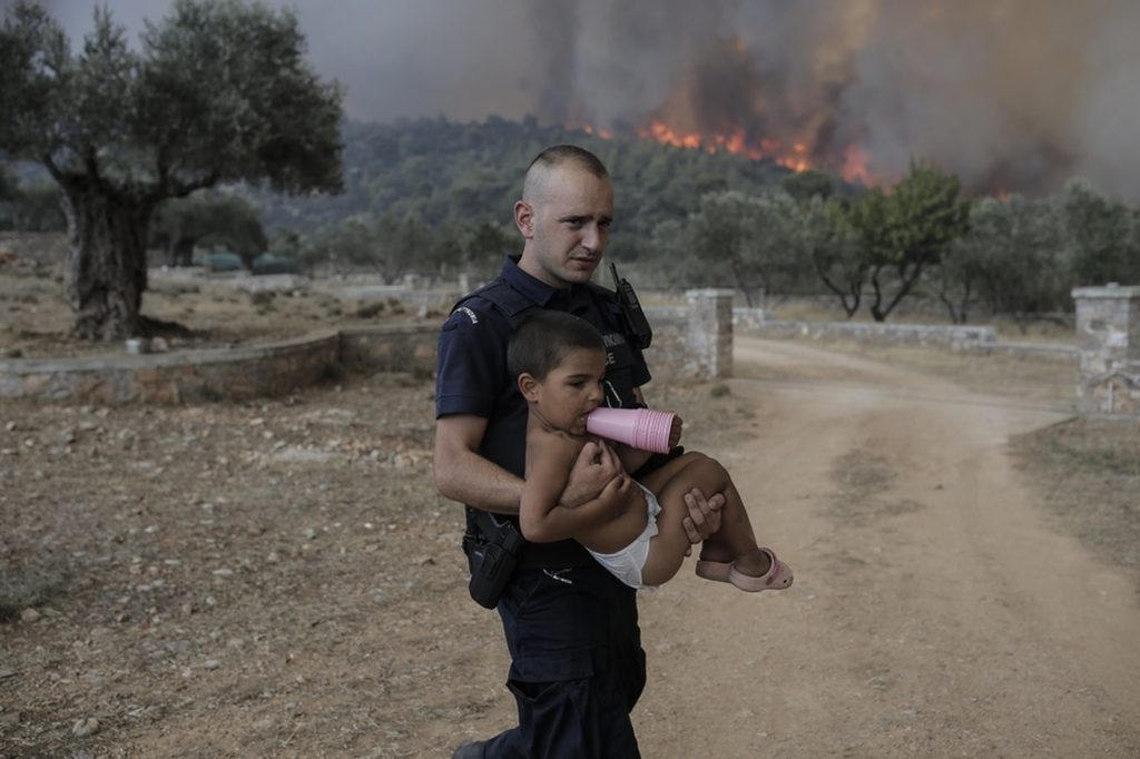 Πρωτοσέλιδο στα βρετανικά ΜΜΕ οι φωτιές της Ελλάδας και ο αστυνομικός που μετέφερε παιδί στα Δερβενοχώρια (φώτο)